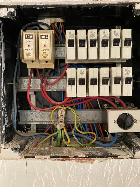 Verouderde open zekeringkast met oude automaten en onoverzichtelijke bedrading